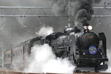 black train on rail and showing smoke